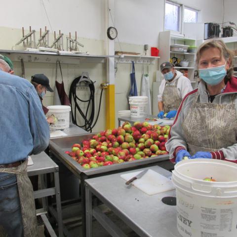 Volunteers wearing face masks cutting apples in a kitchen